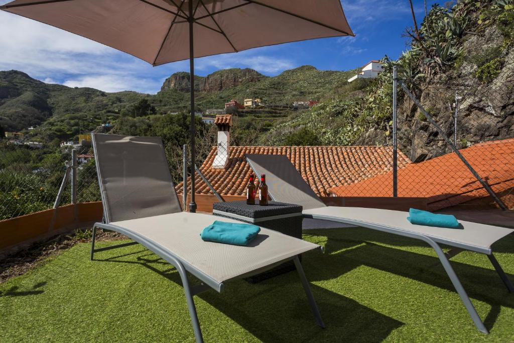 テロルにあるCasa Rural La Escalerillaの庭の上に椅子2脚と傘が置いてある