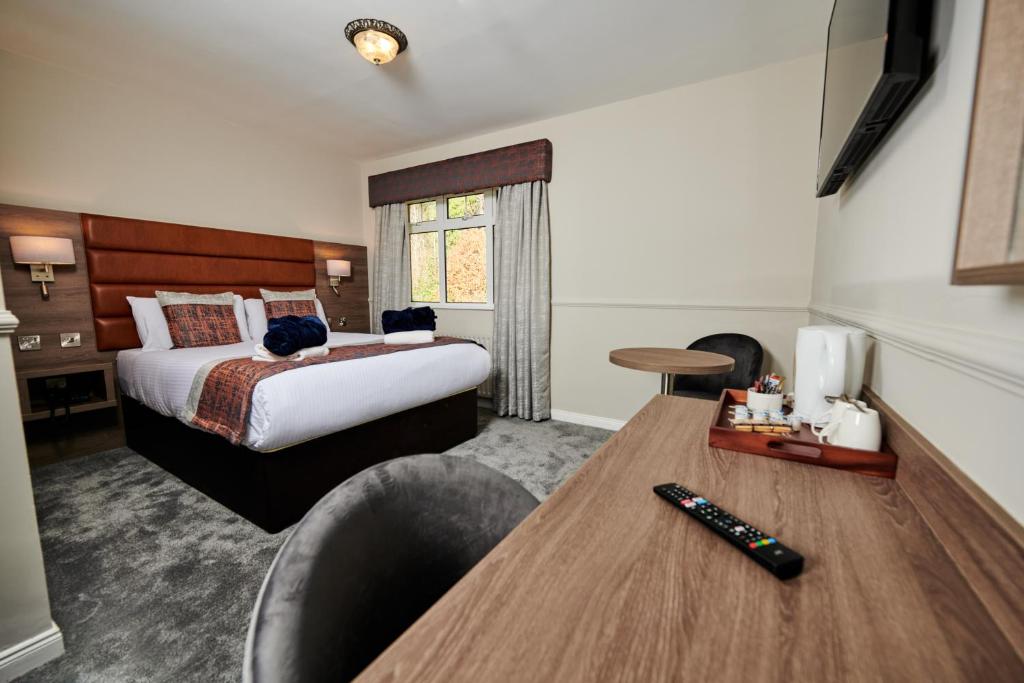 a hotel room with a bed and a desk with a remote control at Bushtown Hotel & Spa in Coleraine