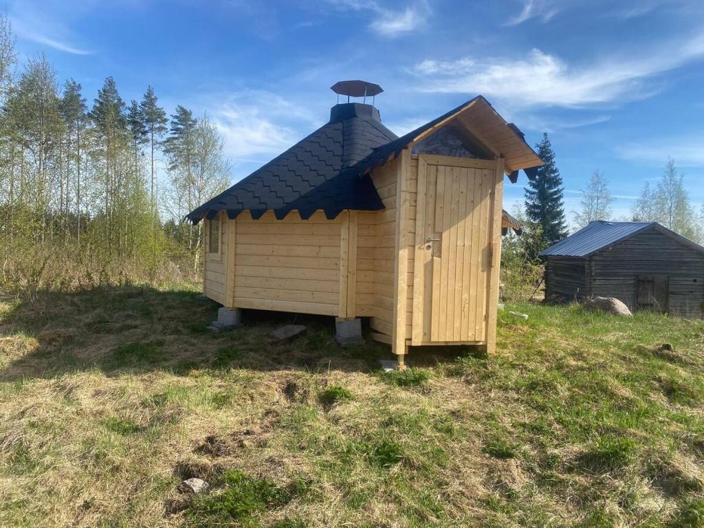 uma pequena casa de madeira com um telhado num campo em Triangle Cabin em Laitila
