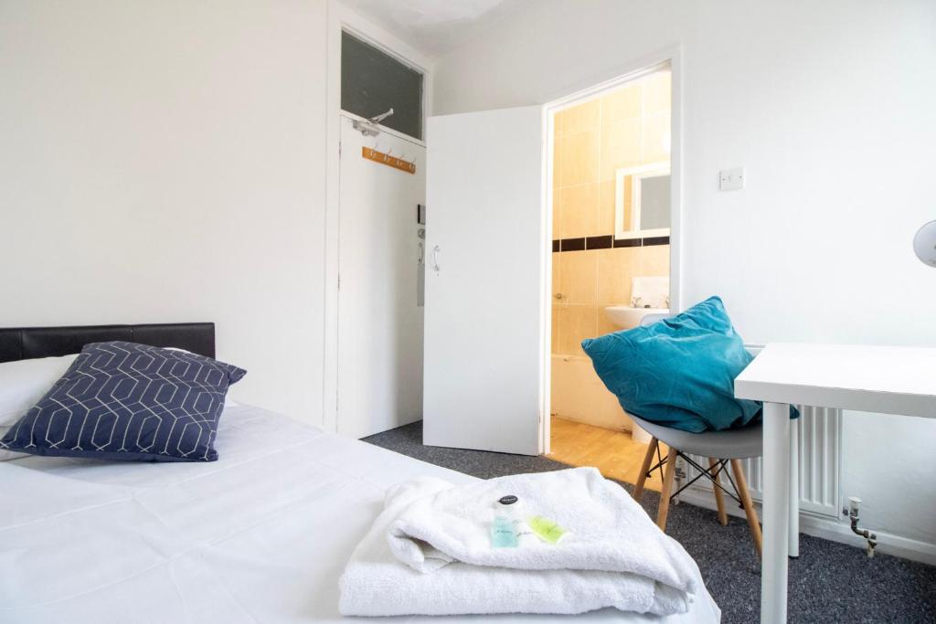 a bedroom with a bed with a blue pillow and a desk at Pebbles guest house in Southampton