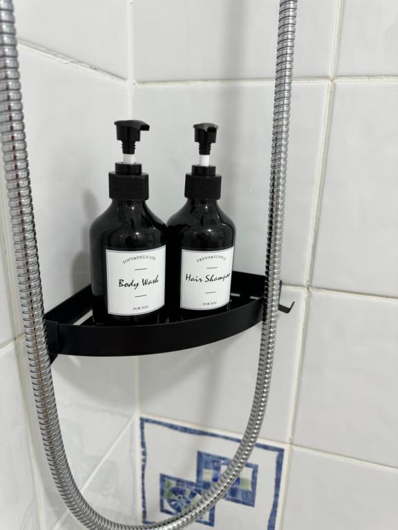 two bottles of soap sitting on a shelf in a bathroom at Garden Place in Clevedon