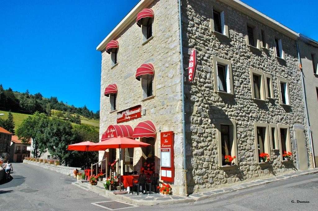 um edifício de pedra com guarda-chuvas vermelhos em frente em Au Parfum des Bois em Saint-Cirgues-en-Montagne