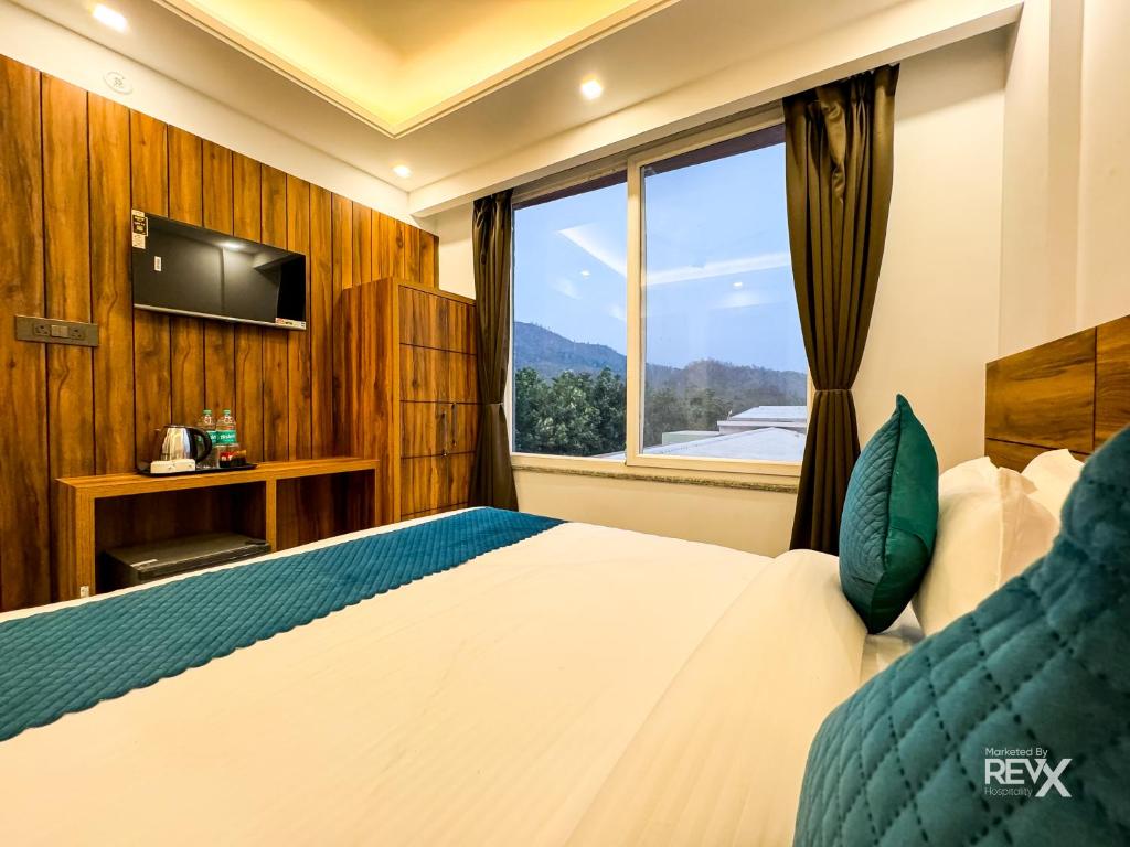 a hotel room with a bed and a window at Hotel Vaidik Ganga , Near Parmarth Niketan in Rishīkesh