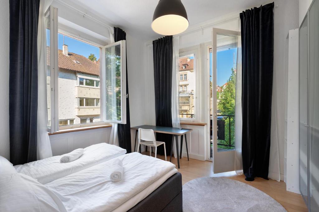 een slaapkamer met een bed, een bureau en ramen bij Die Bleichstraße in Pforzheim