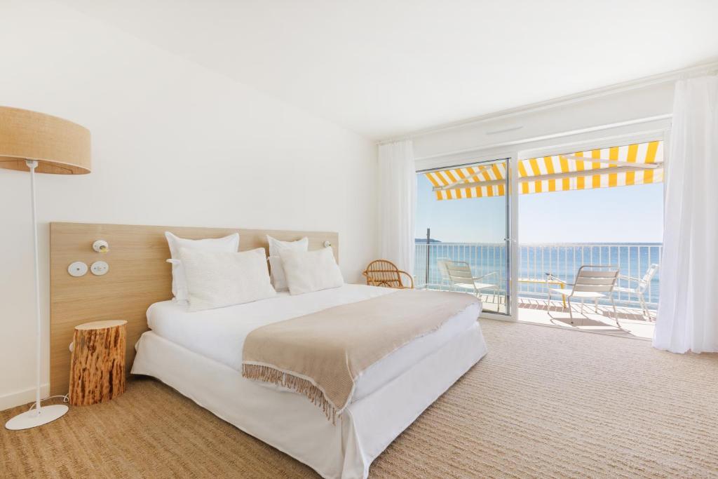 a bedroom with a large bed and a large window at Belle Vue Hôtel in Cavalaire-sur-Mer