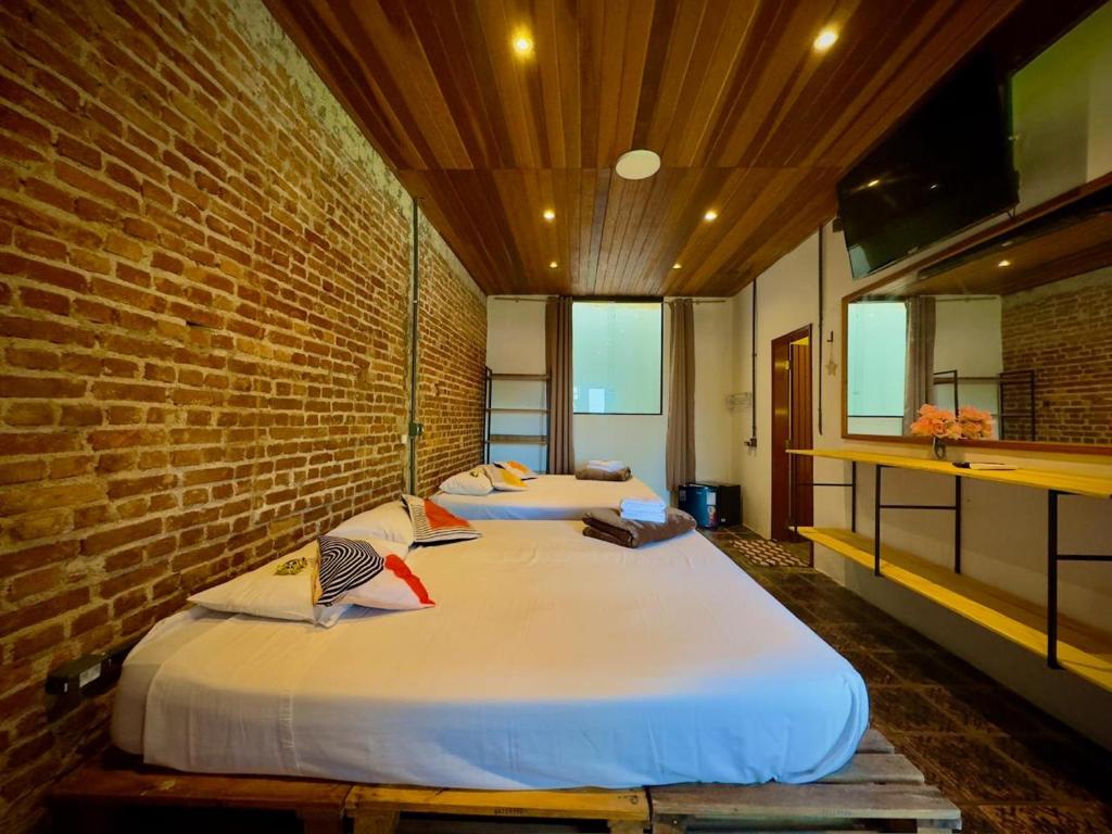 two beds in a room with a brick wall at Refúgio da Enseada - Suítes in Ubatuba