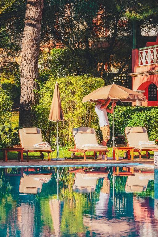 a man standing under an umbrella next to a pool at Domaine de l'Astragale in Saint-Tropez