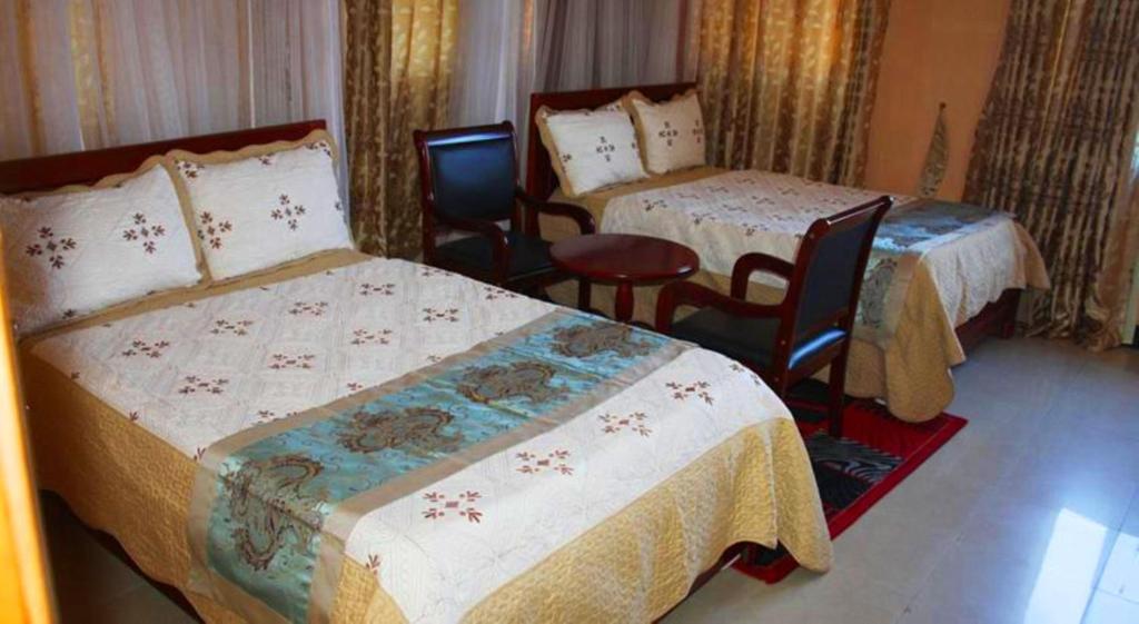 a hotel room with two beds and two chairs at Pearl Highway Hotel Kibuye Kampala in Kampala