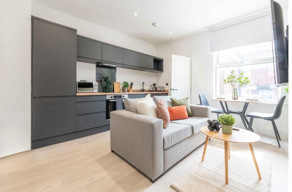 a living room with a couch and a table at Modern 1 Bedroom Flat near Leeds City with Free Parking, Ideal for Contractors & Long Stays - NordStay in Hunslet