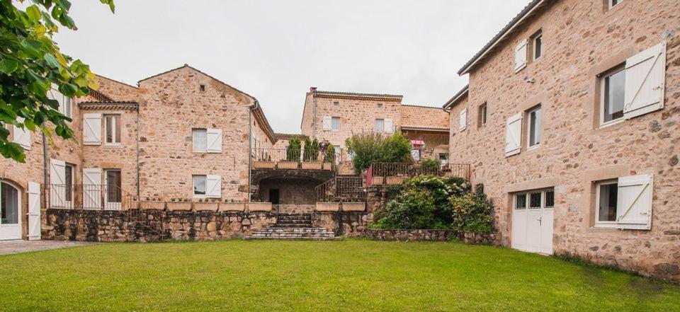 a large brick building with a yard in front of it at Goulapie, Village de gîtes in Saint-Quentin-sur-Sauxillanges