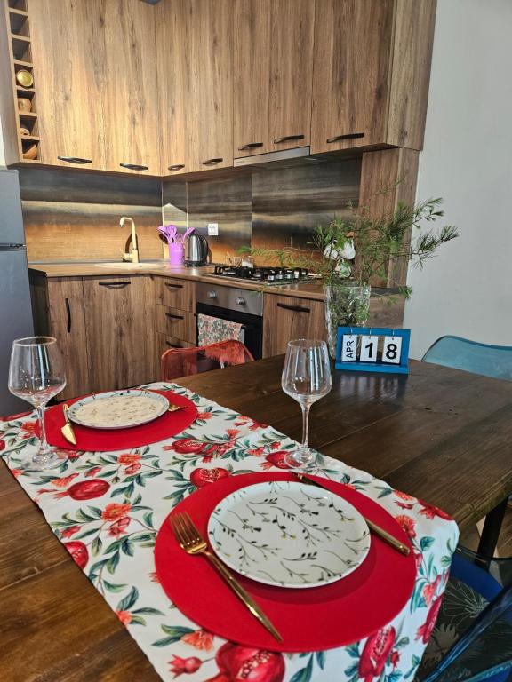 una mesa con dos platos y copas de vino. en WoodStar/ტყის ვარსკვლავი en Ambrolauri