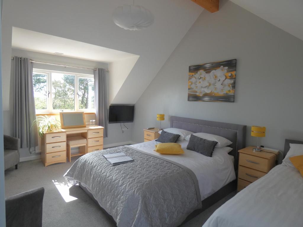 a bedroom with two beds and a desk and a television at Ramblers, Bude in Stratton