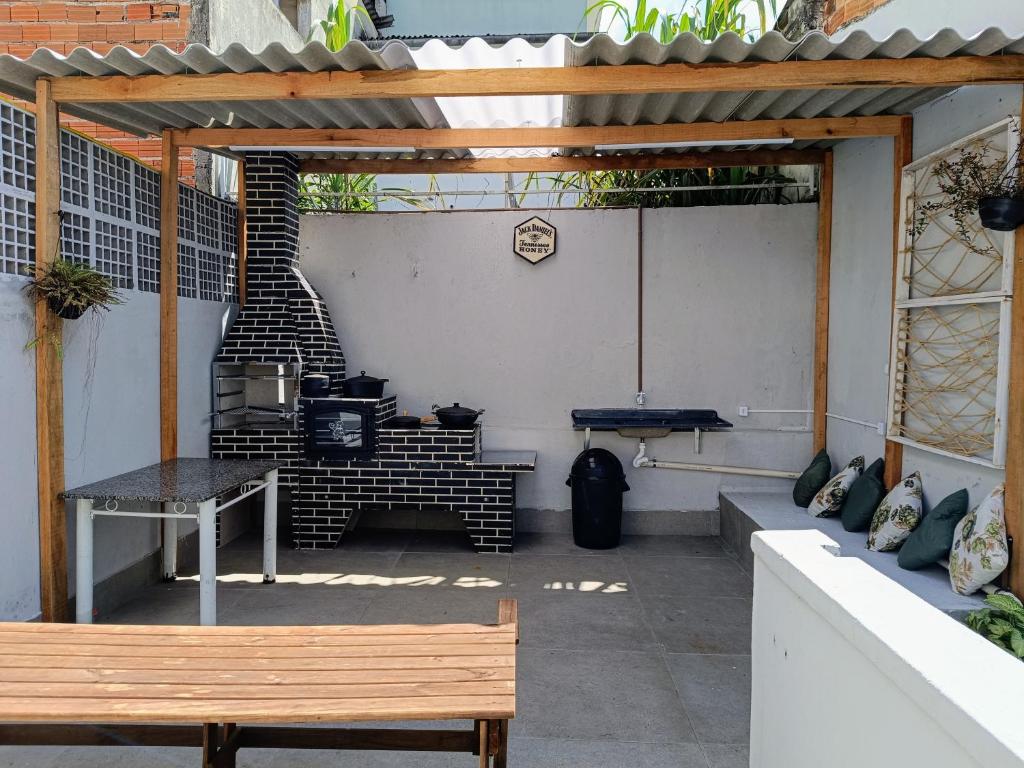 um pátio com um banco, uma mesa e comodidades para churrascos em Encontro Open House em São Paulo