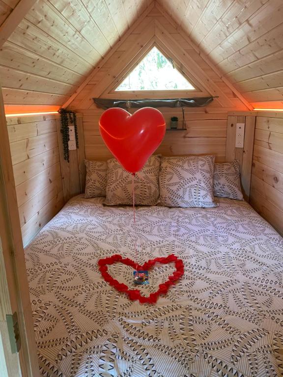a heart balloon on a bed in a cabin at Le Tiki de Coucou in Foncine-le-Haut