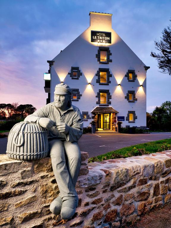 une statue d'un homme assis devant un bâtiment dans l'établissement The Originals City, Hôtel Armen Le Triton, Roscoff, à Roscoff