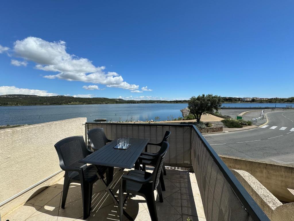 une table et des chaises sur un balcon avec vue sur l'eau dans l'établissement Quai de l'étang, à Gruissan