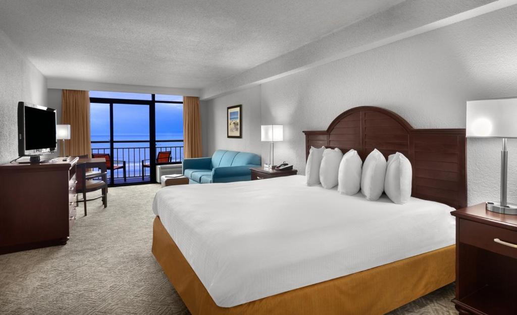 マートルビーチにあるBest Western Ocean Sands Beach Resortの大きなベッドとバルコニーが備わるホテルルームです。
