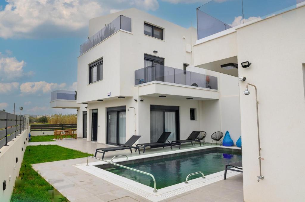 a white house with a swimming pool in front of it at Elegant Villa with Pool in Gournes