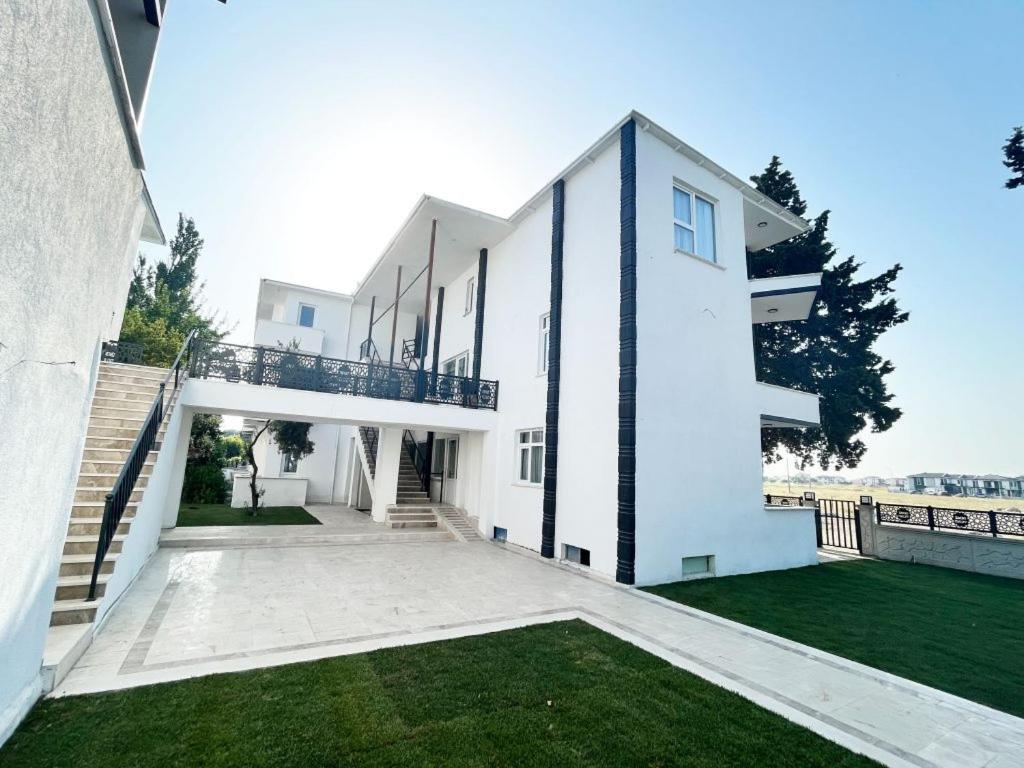 a white house with a balcony and a yard at Ayvalık Denizyıldızı Otel in Ayvalık