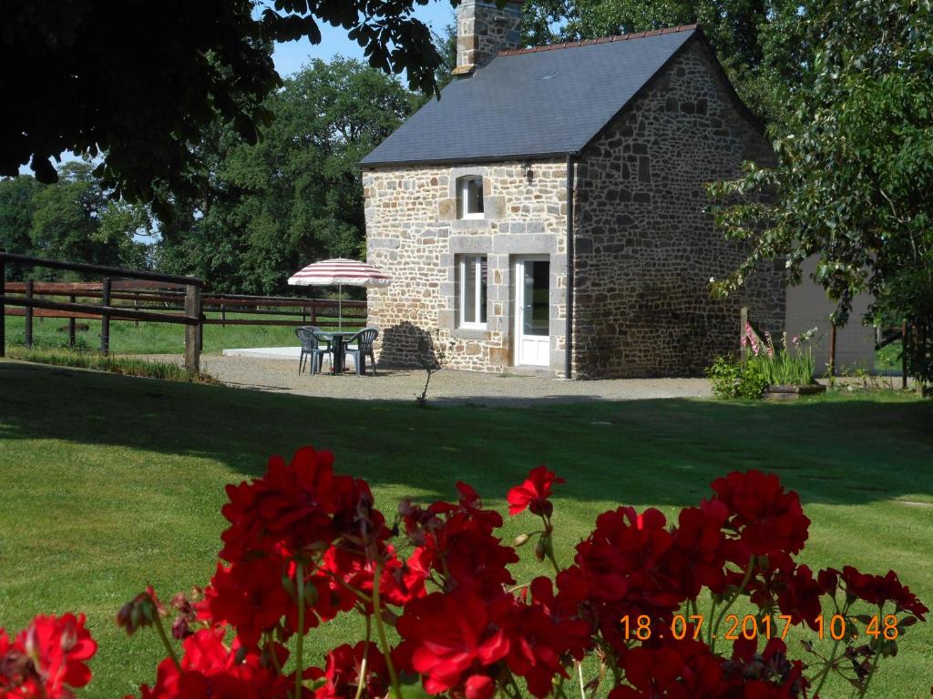 un bâtiment en briques avec une table et des fleurs rouges dans l'établissement Petite maison à la campagne, à Le PARC