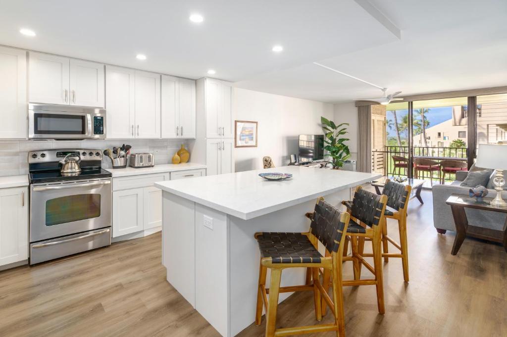 a kitchen with white cabinets and a table and chairs at Kamaole Sands 5-316 in Wailea