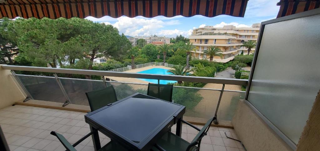 een balkon met een tafel en stoelen en een zwembad bij MIOUGRANO 2 Pieces Climatise 47m2 Piscine, Parking in Fréjus