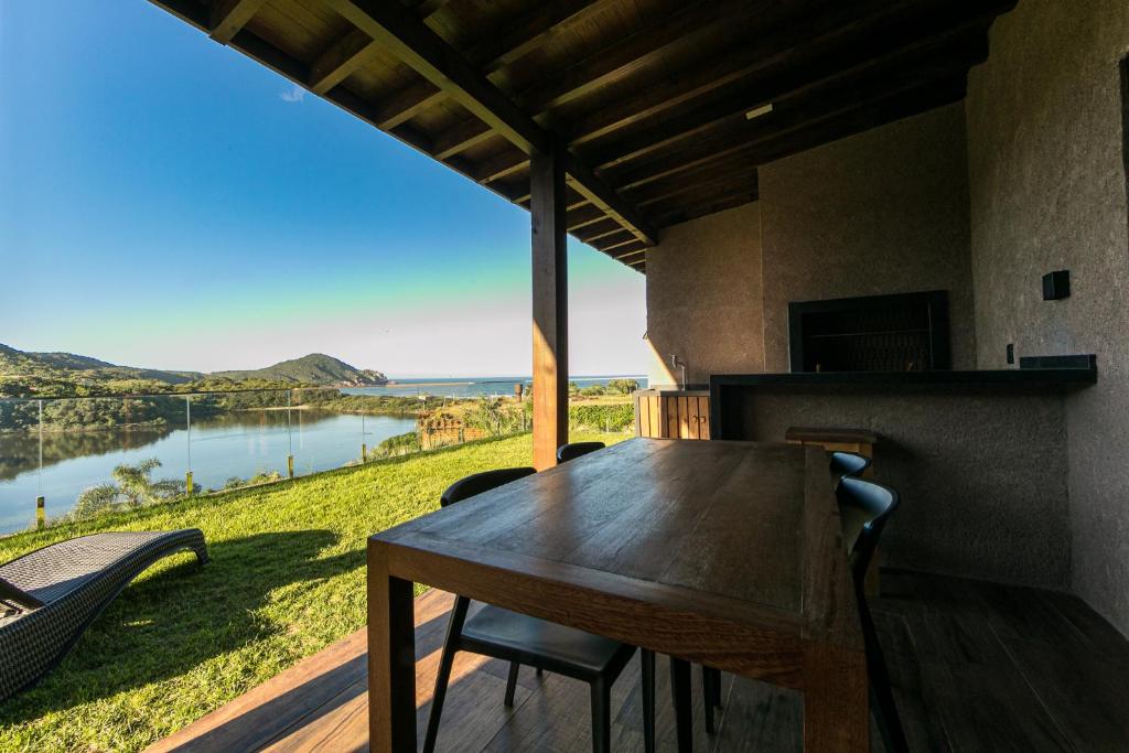 a dining room with a table and a view of a river at Fazenda Verde - Praia do Rosa in Praia do Rosa