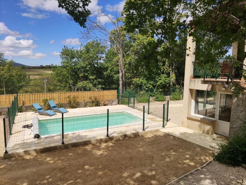 einen Pool mit zwei Stühlen neben einem Haus in der Unterkunft Maison confortable à Ansouis dans Le Luberon in Ansouis