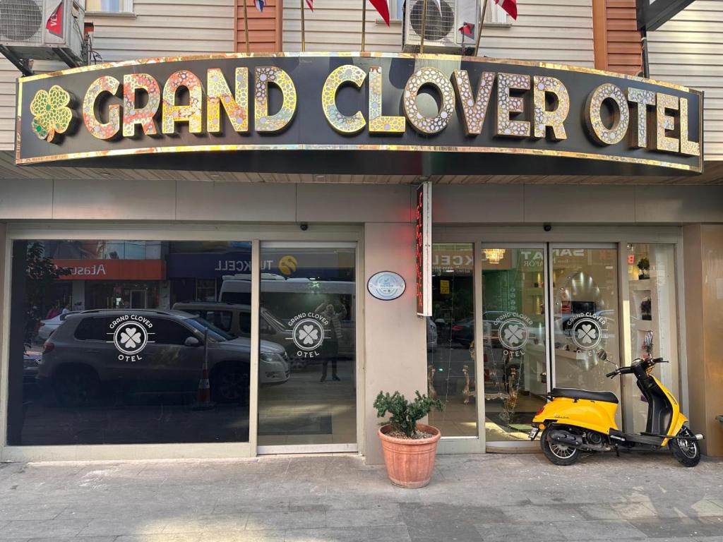 uno scooter parcheggiato di fronte a un grande negozio di trifoglio. di Grand Clover Otel a Seyhan