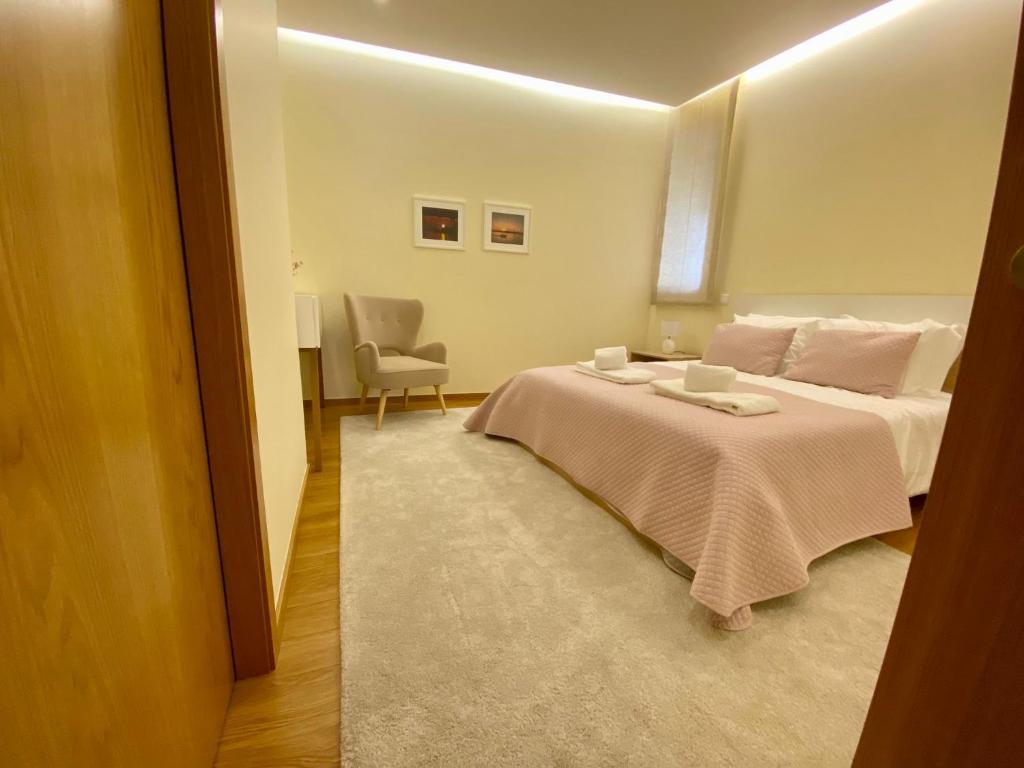 a bedroom with a large bed and a chair at Almeida's House in Viana do Castelo