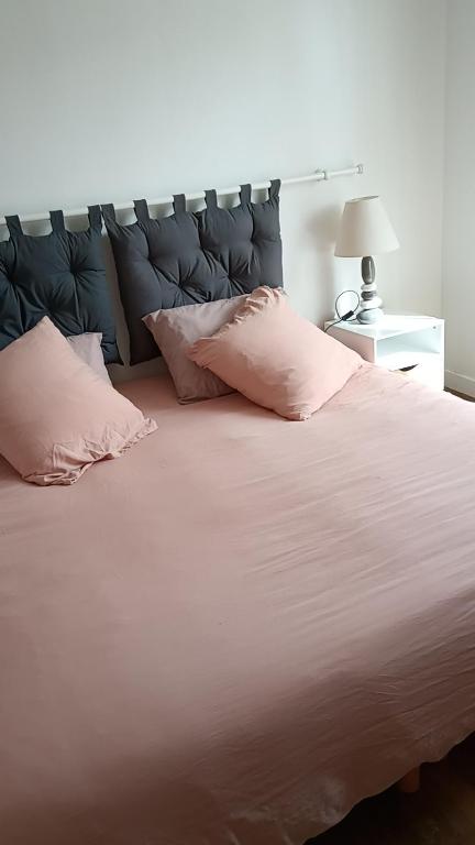 une chambre avec un grand lit avec des oreillers roses dans l'établissement Gîte Le well wazh, à Plouray