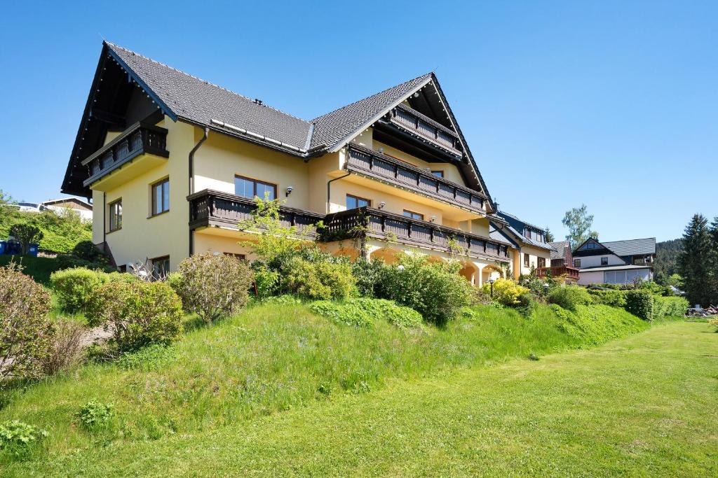 a large yellow house on a hill with a yard at Pension Bergblick in Marienberg