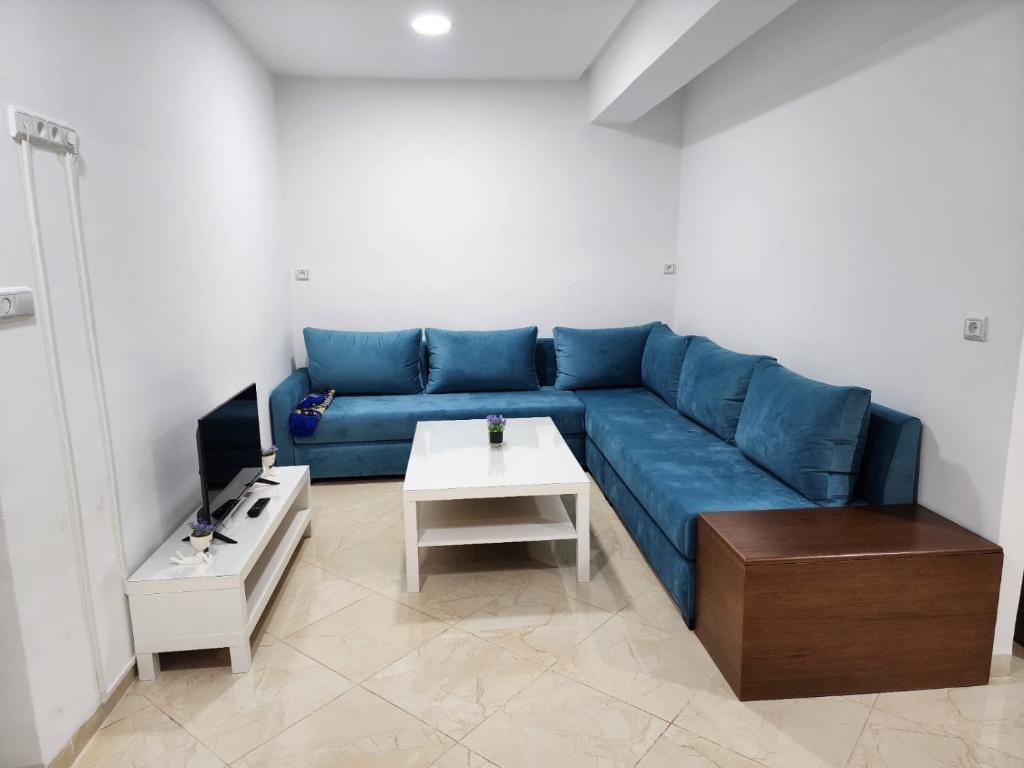 Una sala de estar con un sofá azul y una mesa. en Appartements climatisés JANYA HOLIDAYS, en Alhucemas