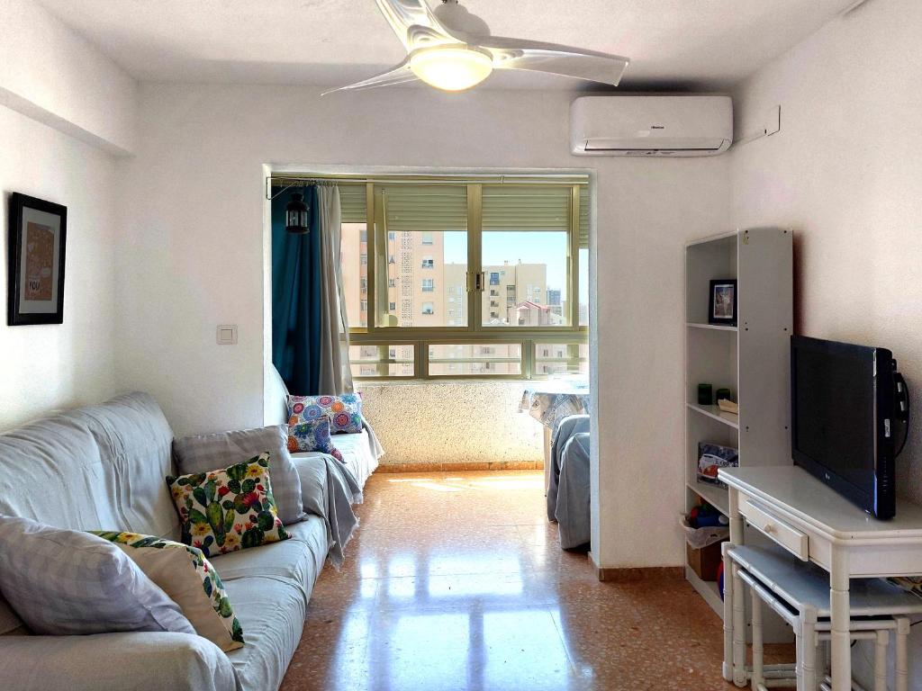 sala de estar con sofá y TV en Apartamento Mariscal 4, 13 con piscina y vistas al mar, en Benidorm