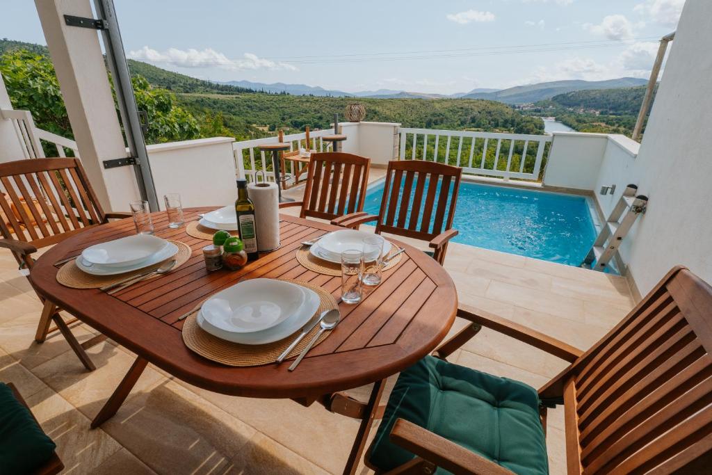 a wooden table with plates and wine glasses on a balcony at Villa Wolf in Čapljina