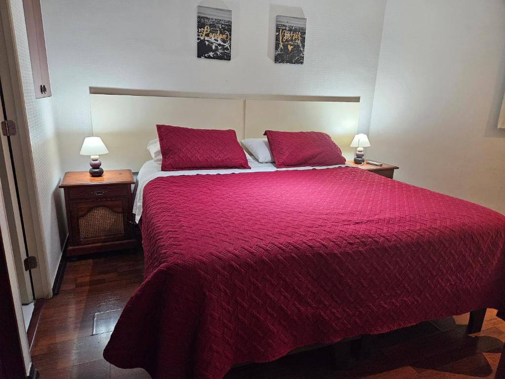a bedroom with a large bed with a red blanket at San Ignacio Suite Apartments in Santiago