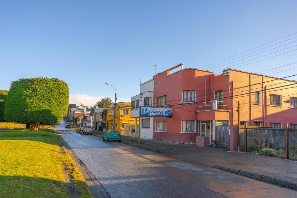 una calle urbana vacía con edificios coloridos y un coche verde en Hotel Condor de Plata, en Punta Arenas