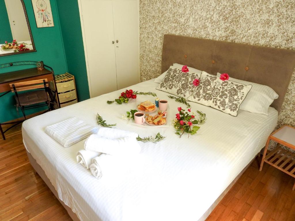 ein Bett mit einem Tablett mit Essen und Blumen darauf in der Unterkunft Green ART House Athens in Athen