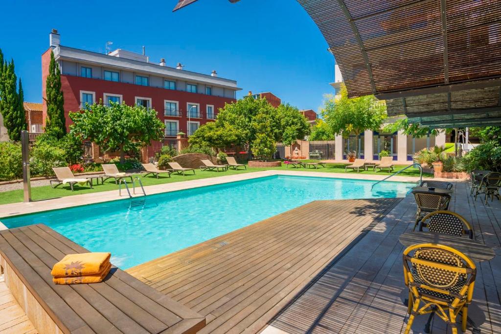蒙特布里奧戴爾坎普的住宿－聖約迪酒店，一座带木制甲板和椅子的游泳池以及一座建筑