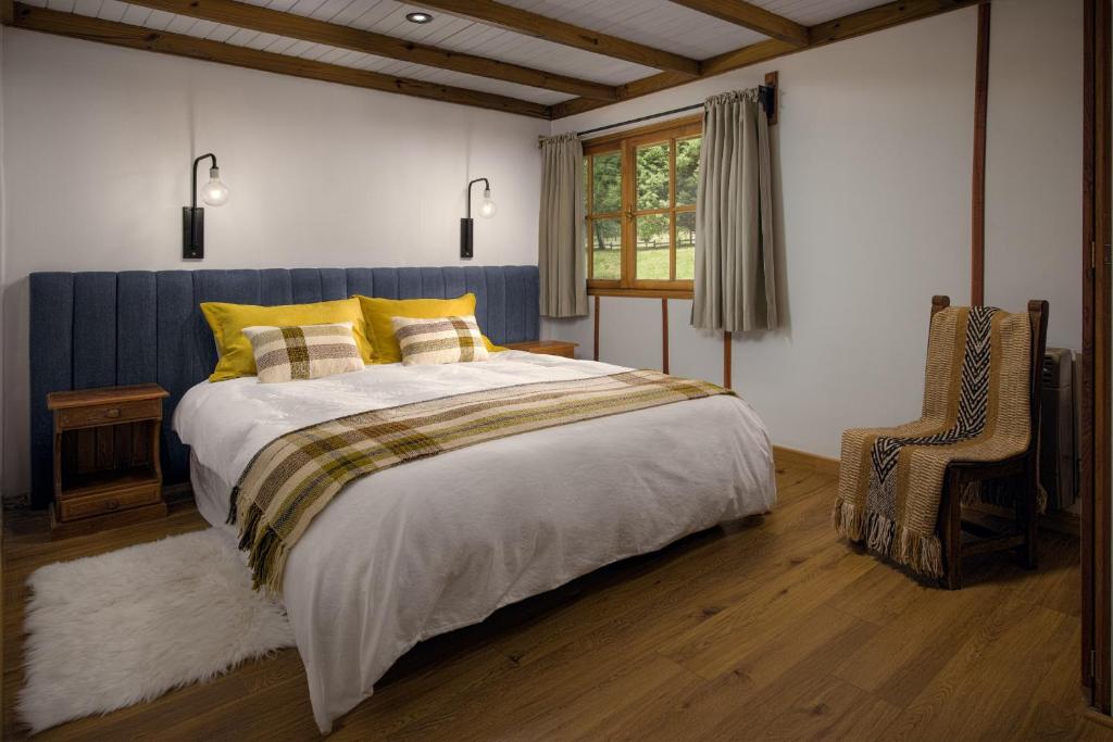 1 dormitorio con 1 cama grande y 1 silla en Spring Creek Lodge en Junín de los Andes