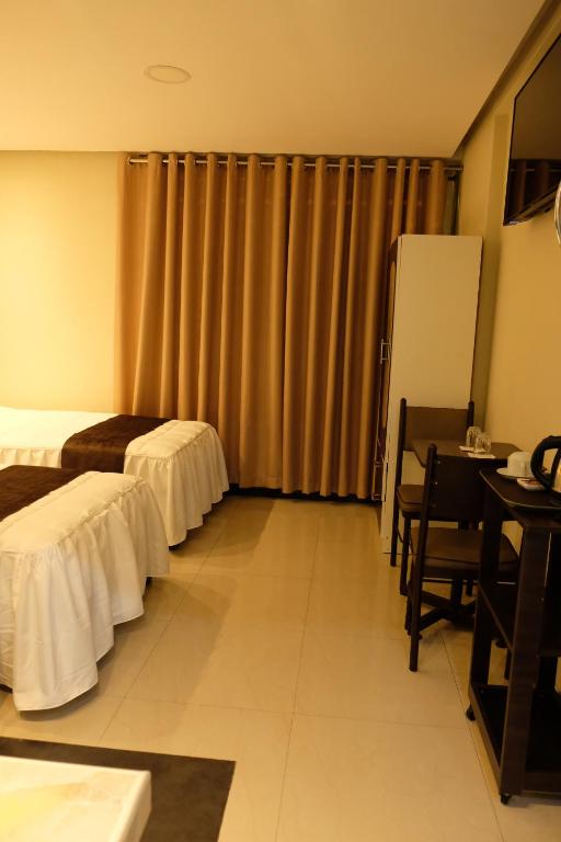 a hotel room with two beds and a desk at Hotel Puma'r Tacna in Tacna