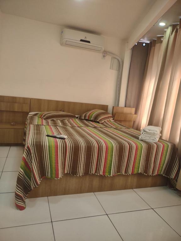 Bett mit gestreifter Decke in einem Zimmer in der Unterkunft AP da Cris cabo frio in Cabo Frio
