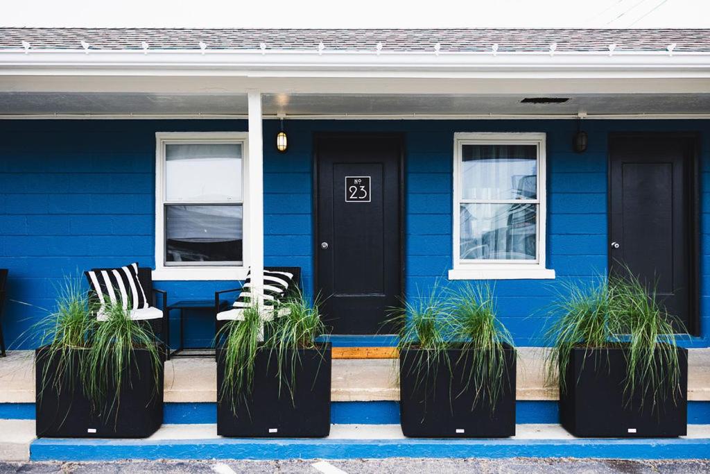 a blue house with two chairs and a black door at Seabirds Motel At Kure Beach in Kure Beach