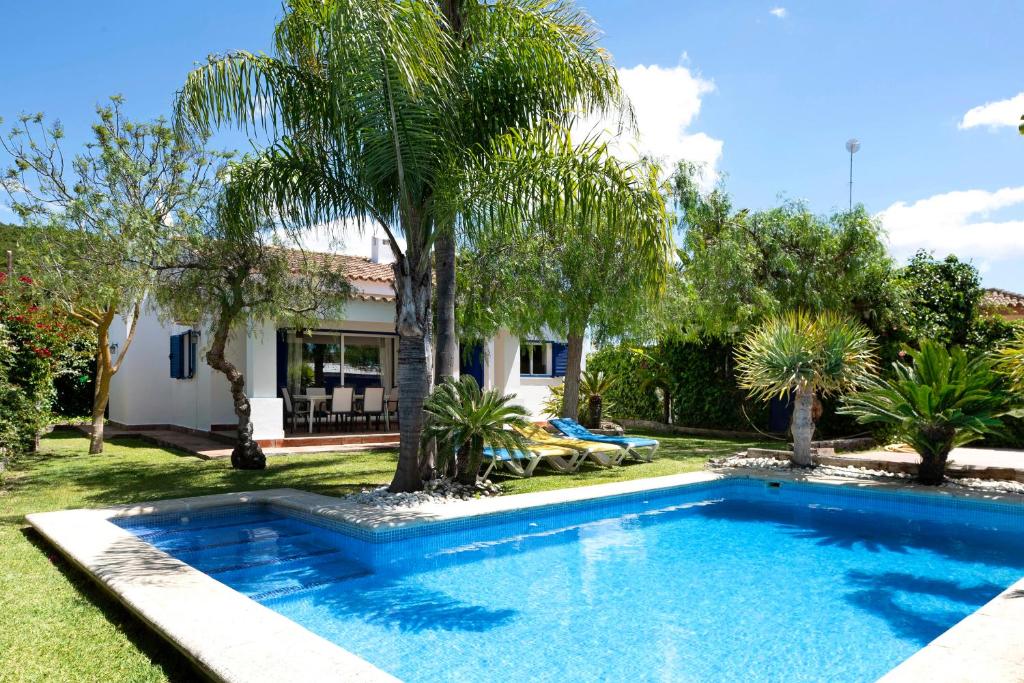 a swimming pool in front of a house with palm trees at Villa Amura - Solo Familias in Conil de la Frontera