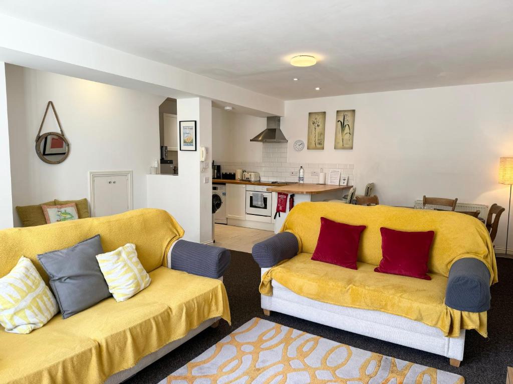 ヘイスティングスにあるModern house in central St Leonardsのリビングルーム(黄色のソファ2台付)、キッチンが備わります。