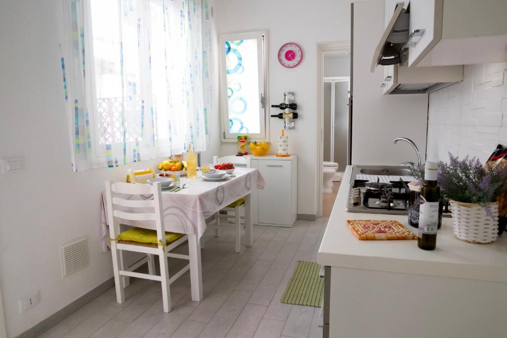 una cucina bianca con tavolo e sedie bianchi di Casa Vacanze La Coccinella a Trapani