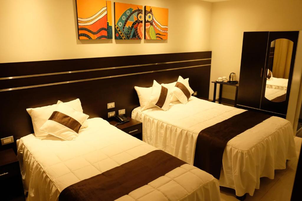 a hotel room with two beds and a mirror at Hotel Puma'r Tacna in Tacna