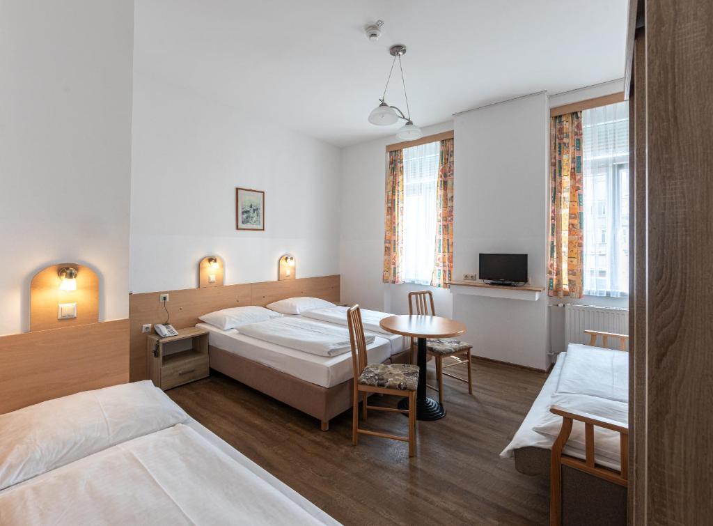 um quarto de hotel com duas camas e uma mesa em Hotel Terminus em Viena
