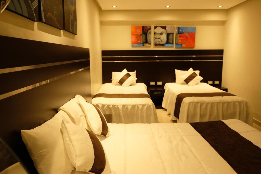 a hotel room with two beds with white sheets at Hotel Puma'r Tacna in Tacna