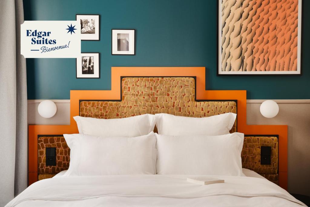 Bett mit orangefarbenem Kopfteil und weißen Kissen in der Unterkunft Edgar Suites Montmartre - Paul Albert in Paris